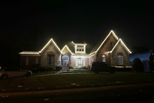 Warm white C9 Christmas lights on a stone two-story home in Middletown, Kentucky